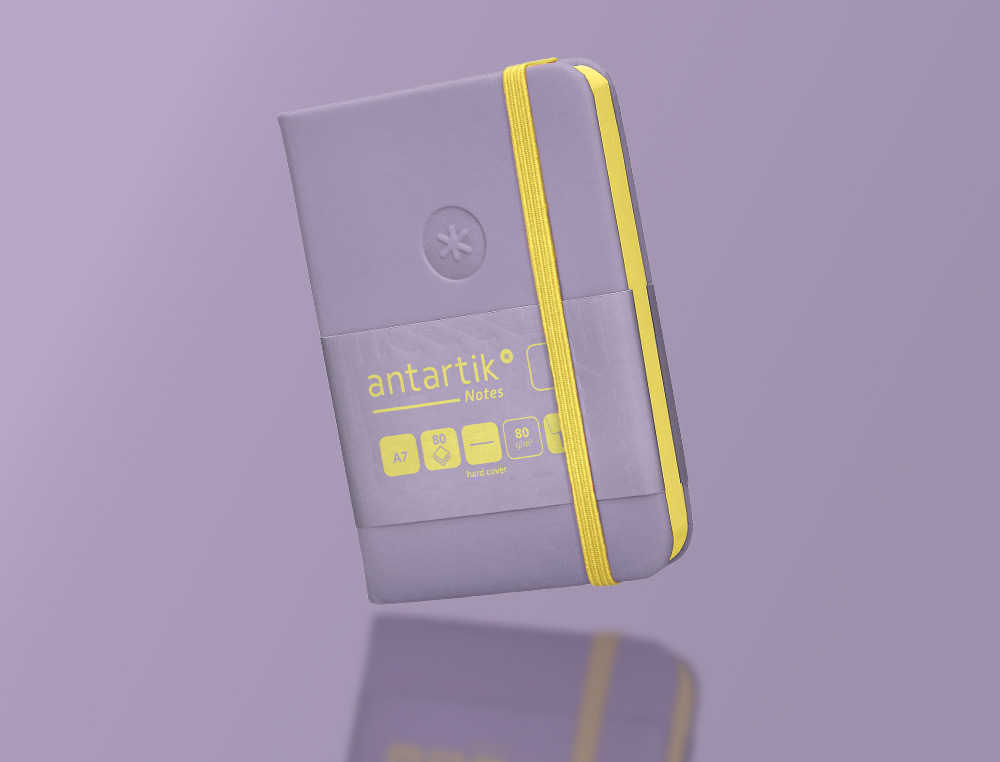 CUADERNO CON GOMILLA ANTARTIK NOTES TAPA DURA A7 HOJAS LISAS MORADO Y AMARILLO 80 HOJAS 80 GR FSC